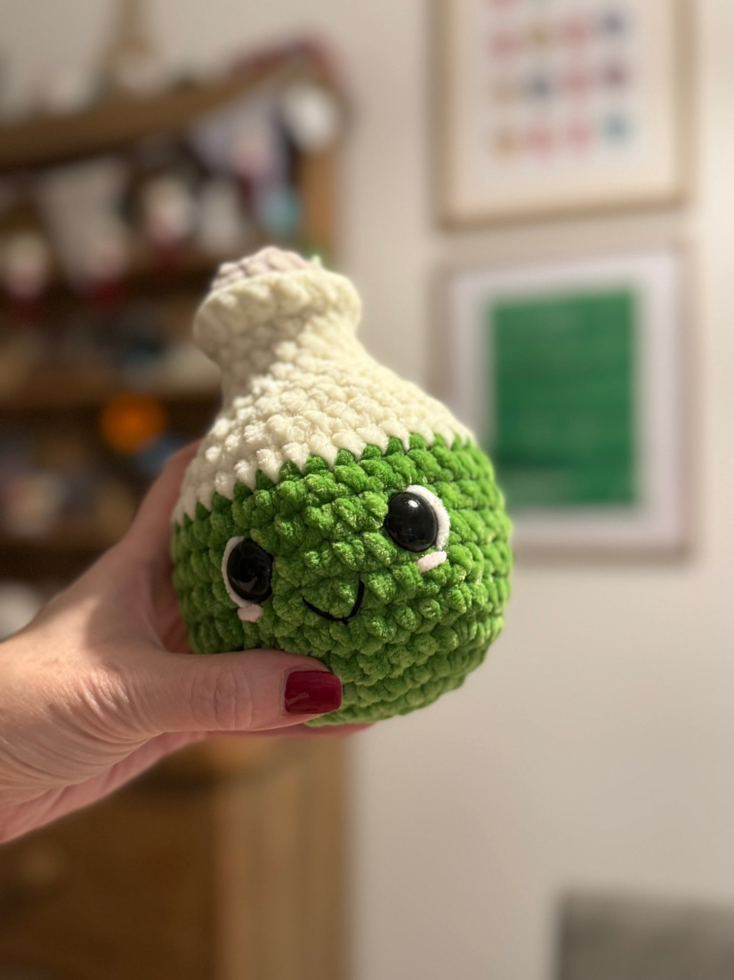 Crochet potion bottle with cute face that is green.