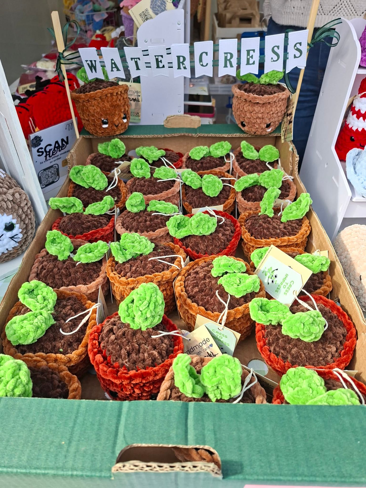 Small crocheted pots with green yarn plants on a table.
