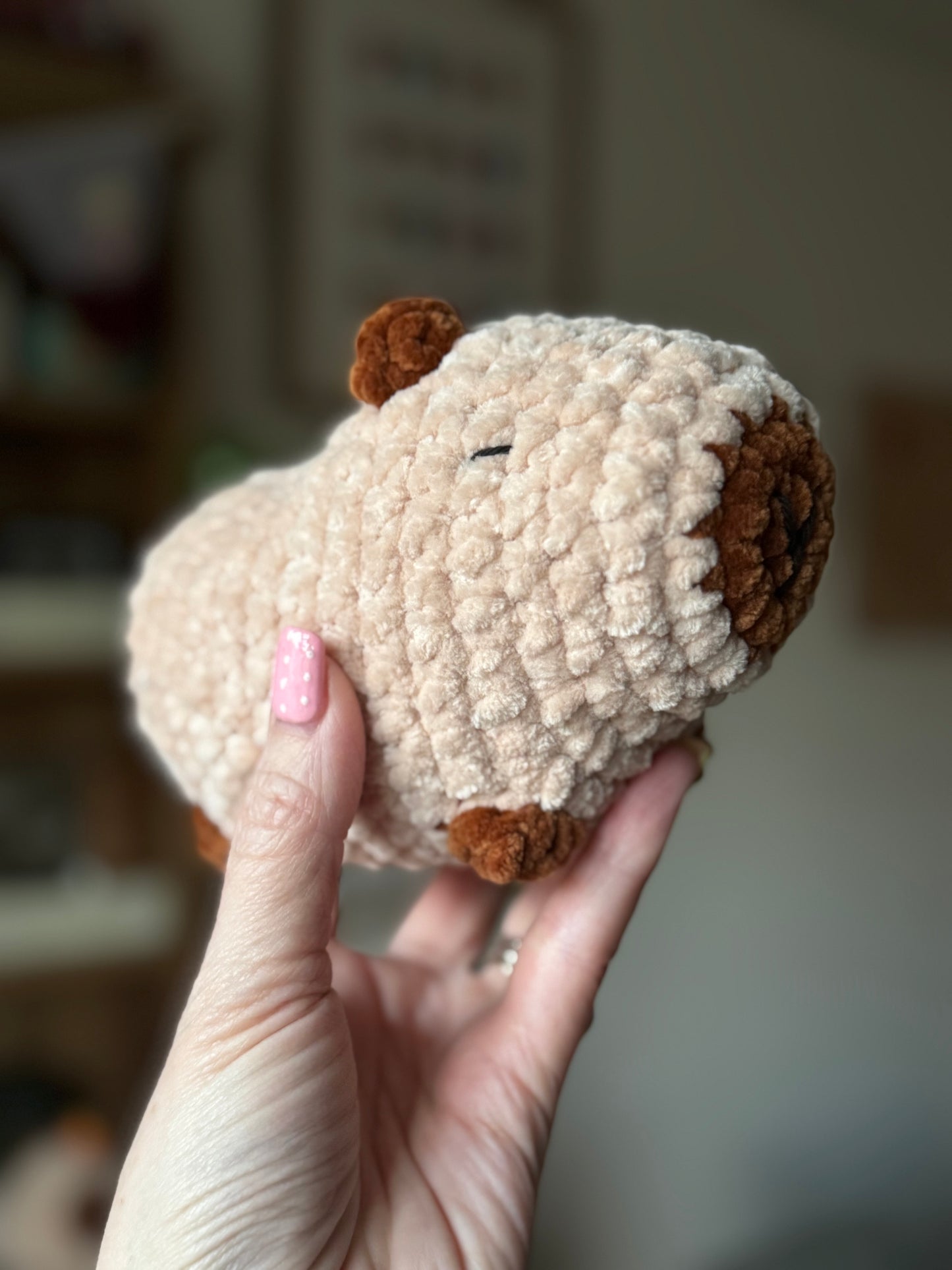 Hand holding a small plush toy with a blurred background
