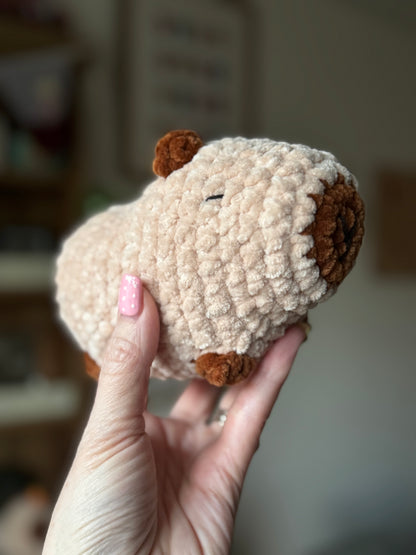 Hand holding a small plush toy with a blurred background
