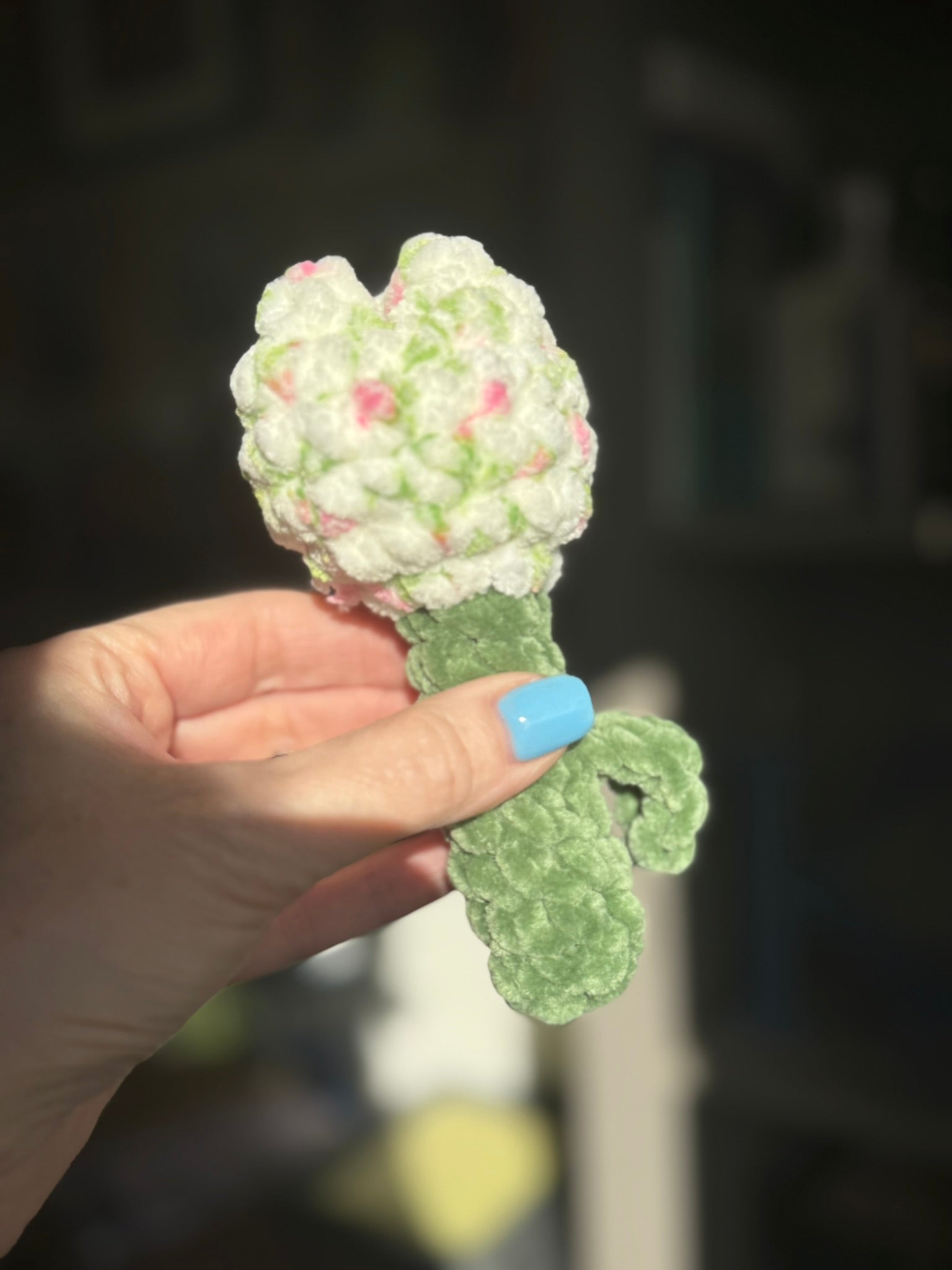 Hand holding a decorative flower-shaped object with a blurred background
