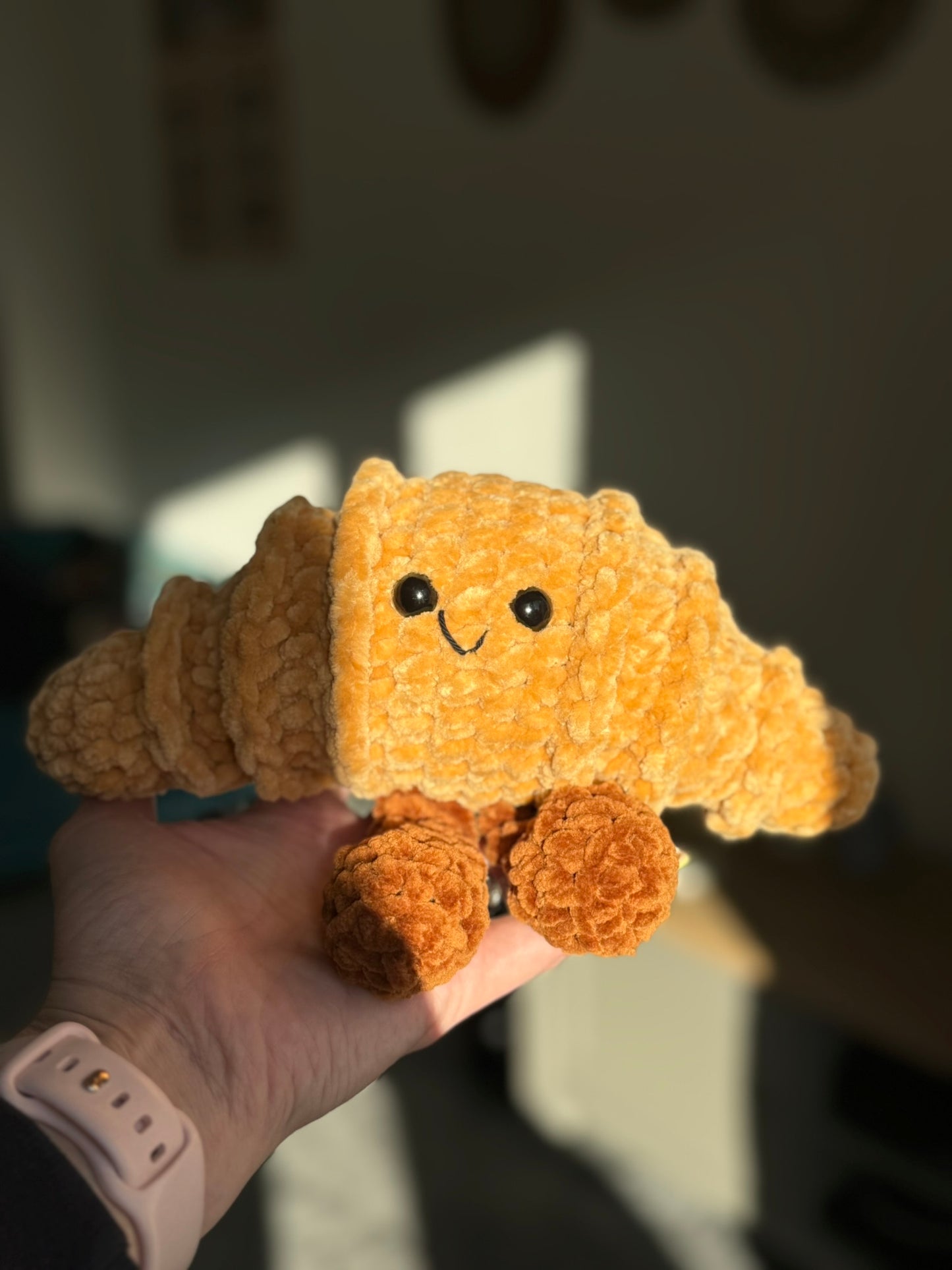 Plush toy resembling a cloud with a smiling face held in a hand against a blurred background