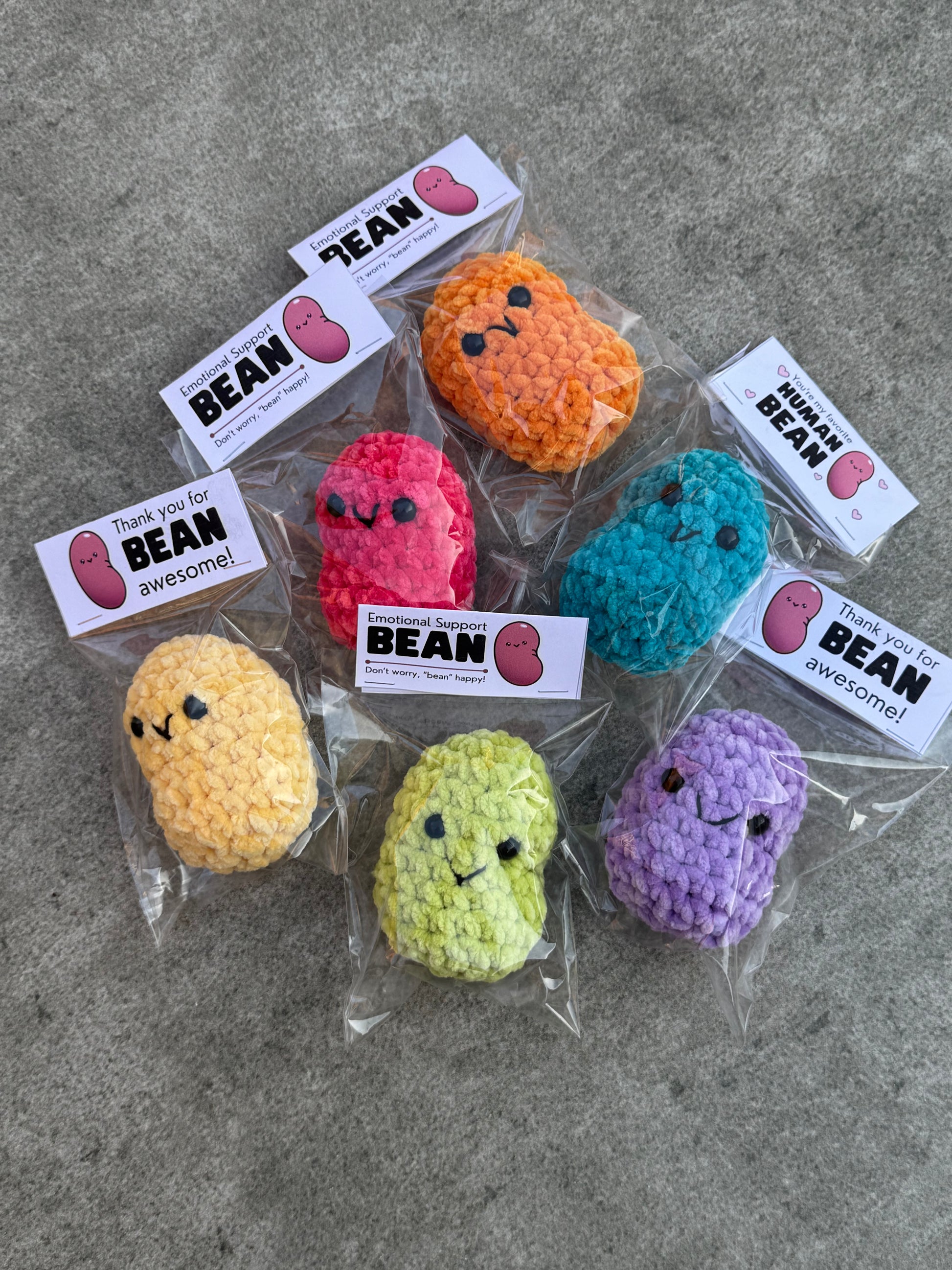 Colorful bean-shaped toys with face designs on a gray surface