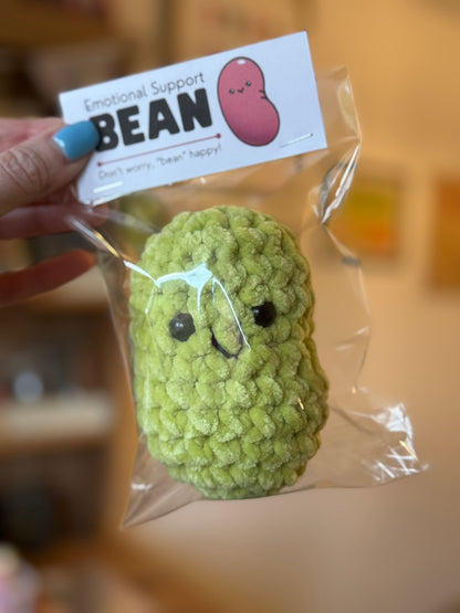 Green plush toy with a 'Bean' label on a blurred background