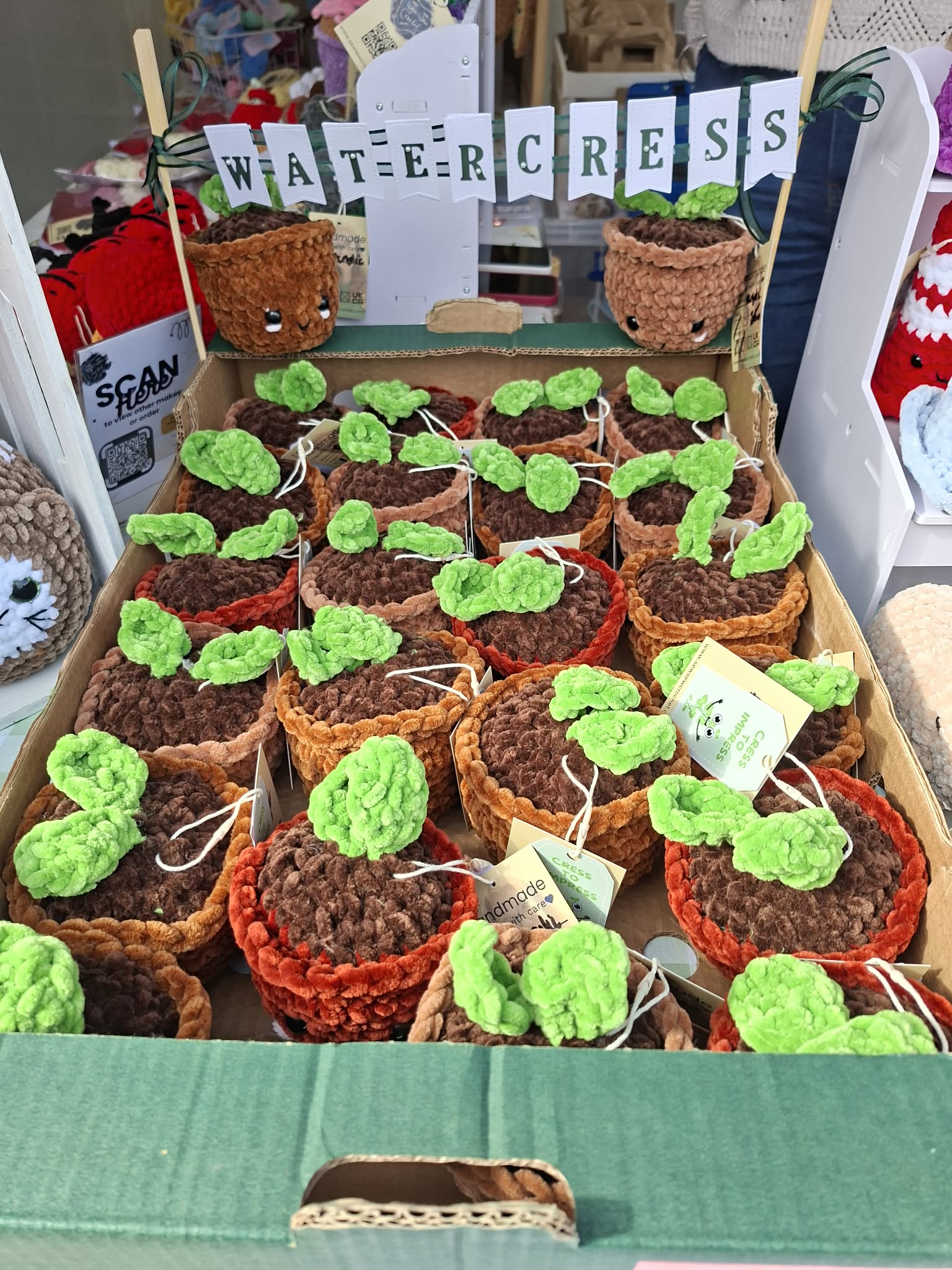 Small crocheted pots with green yarn plants on a table.