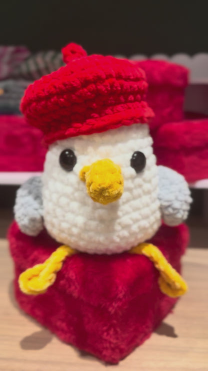 Steven Seagull a crochet gull sitting on a plush heart