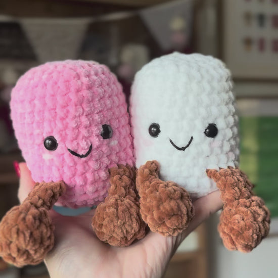 Two Crochet marshmallows sitting on hand