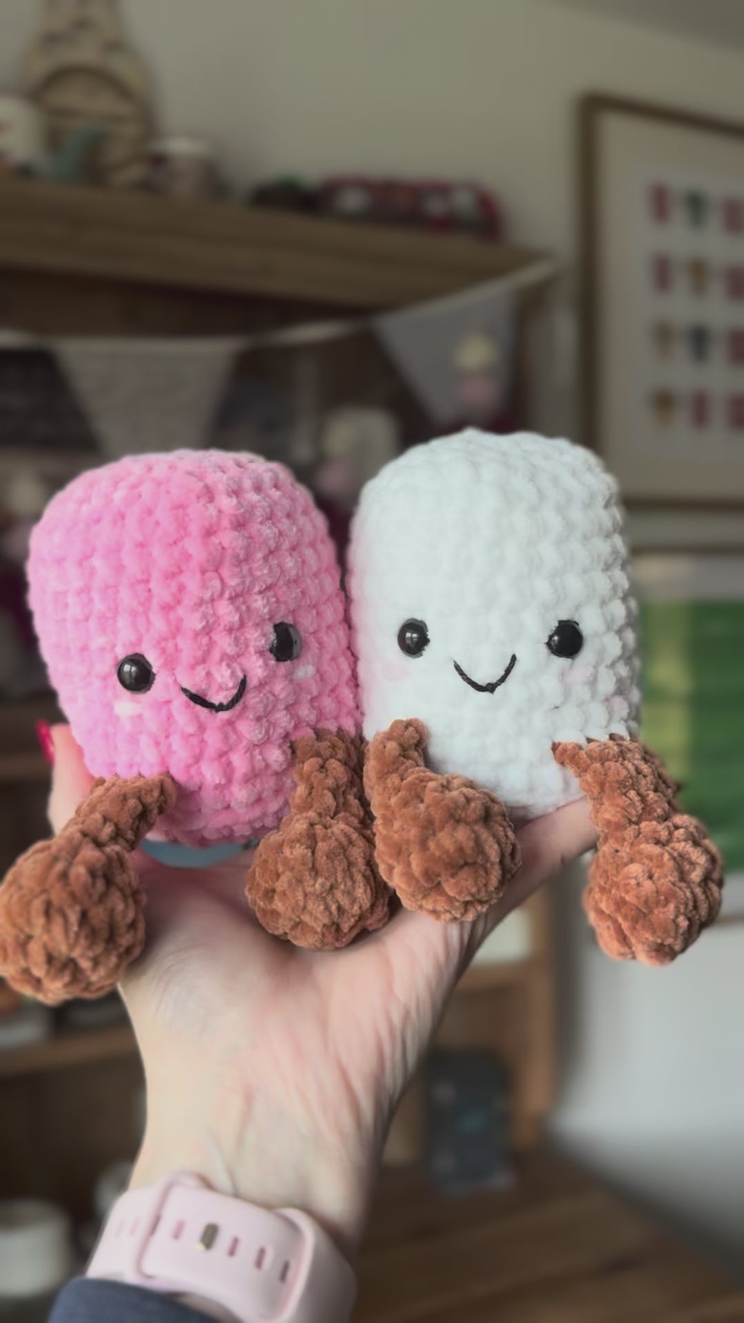 Two Crochet marshmallows sitting on hand